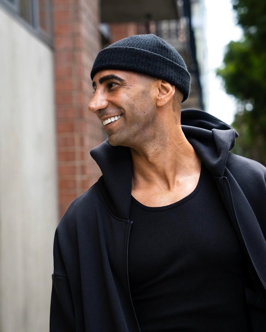 Fousey smiling on a city street in a black beanie and hoodie